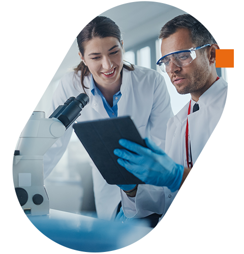 Two medical researchers analyzing data on a tablet in a laboratory with a microscope